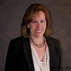 Julie Elledge MCC headshot photo, brown haired woman smiling in black blazer and white top