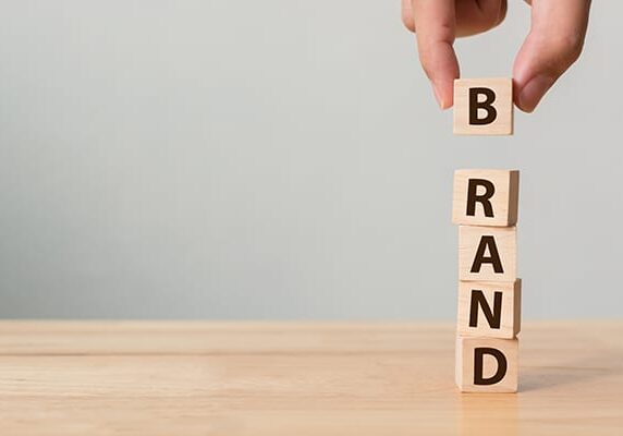 person stacking blocks that spell Brand