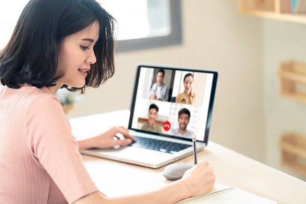 female coach networking via video call with four other professionals and taking notes