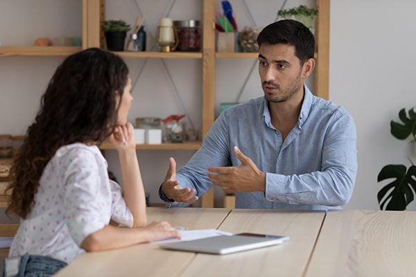 coach and client meeting at a table and the coach is speaking to explain something