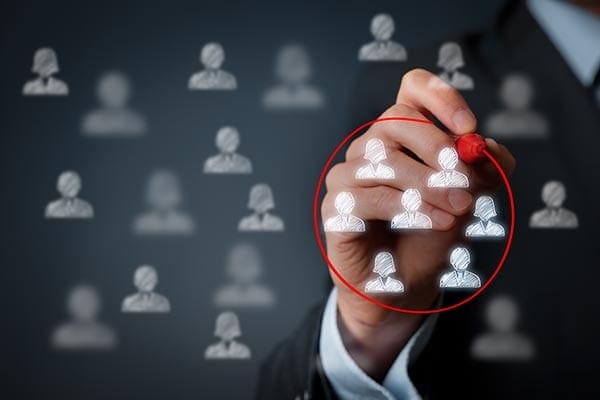 person circling a group of people icons in red on a transparent screen