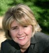 Suzanne Muusers headshot photo, smiling woman with short blond hair wearing black shirt outside