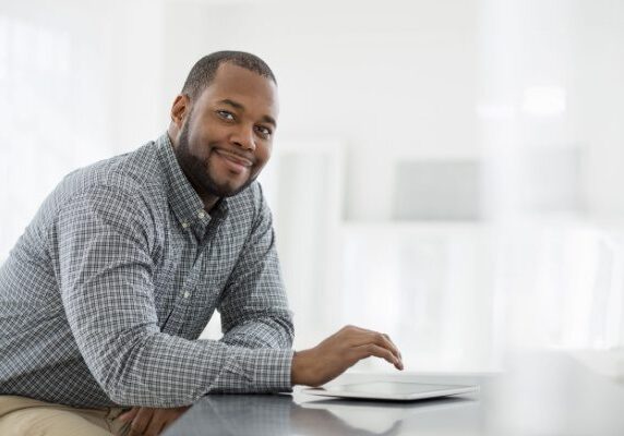 coach sitting at a table with a tablet smiling