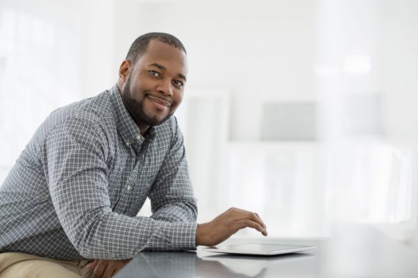 coach sitting at a table with a tablet smiling